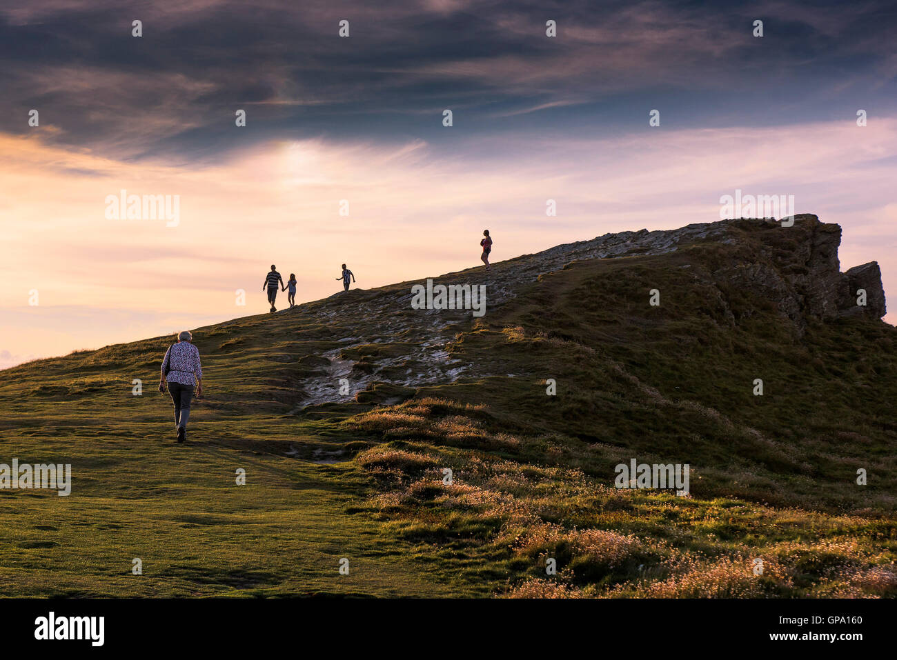 Coucher du soleil comme les vacanciers profitez d'une promenade en fin de soirée sur le sommet de l'île de Porth Newquay, Cornwall. Banque D'Images