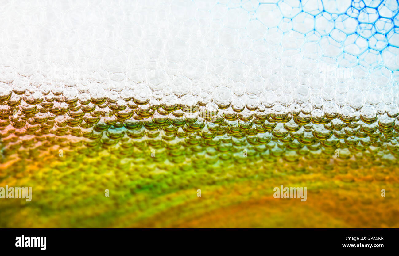 Close-up de dessous de bulles flottant sur l'eau, en colorant de couleur à travers le verre. Banque D'Images