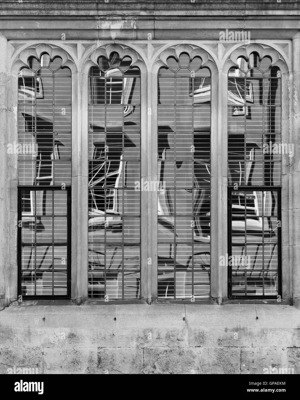 Vieux bâtiment reflète dans quatre fenêtres en pierre décorés en verre au plomb d'un bâtiment historique Banque D'Images