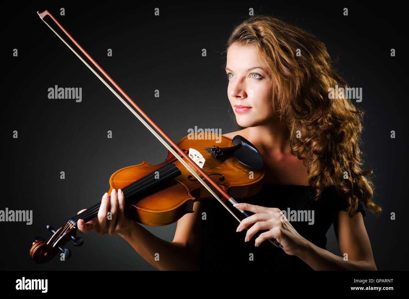 Woman with violin in dark room Banque D'Images