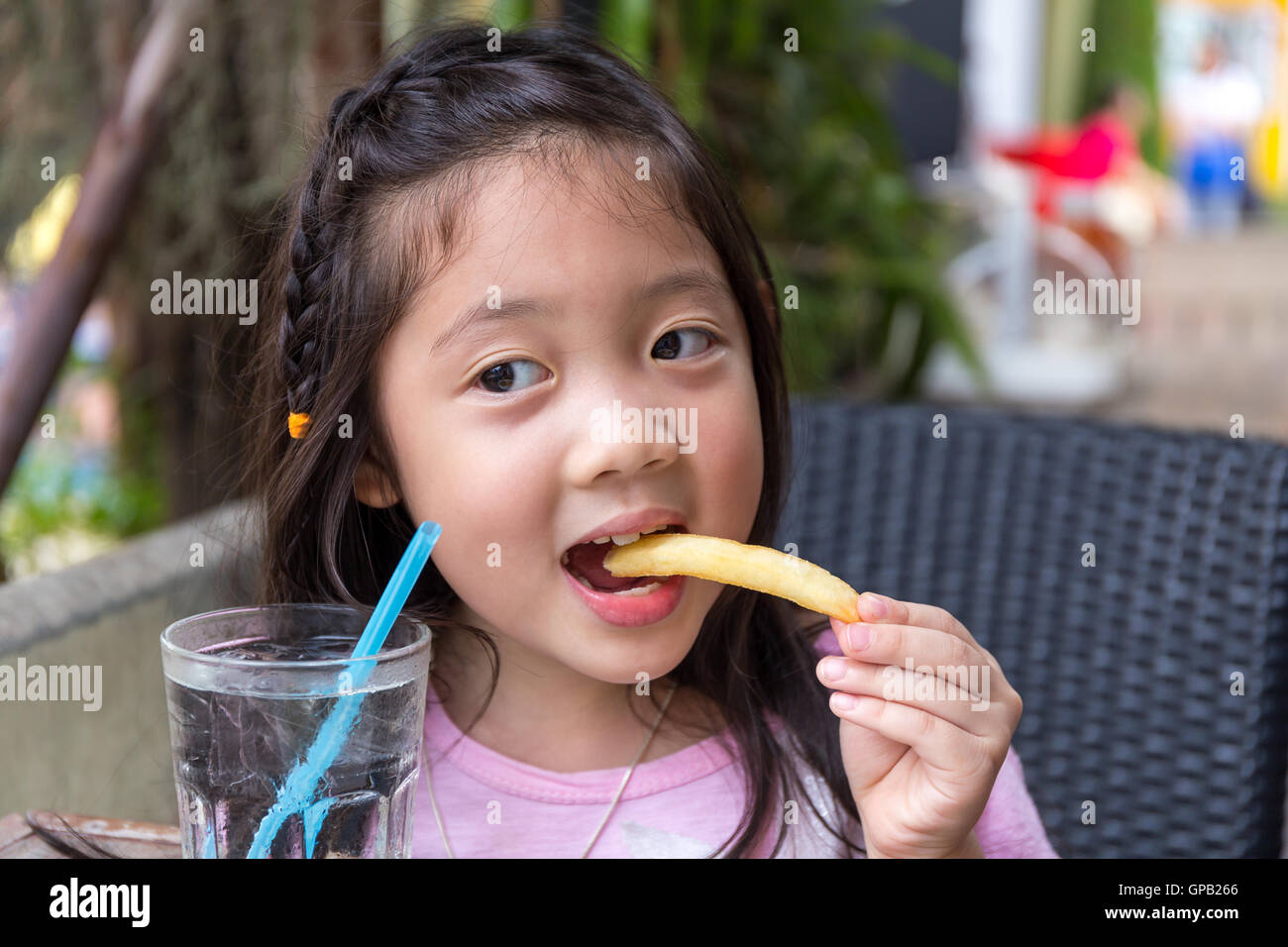 Enfant mangent des frites et de l'eau au restaurant. Banque D'Images
