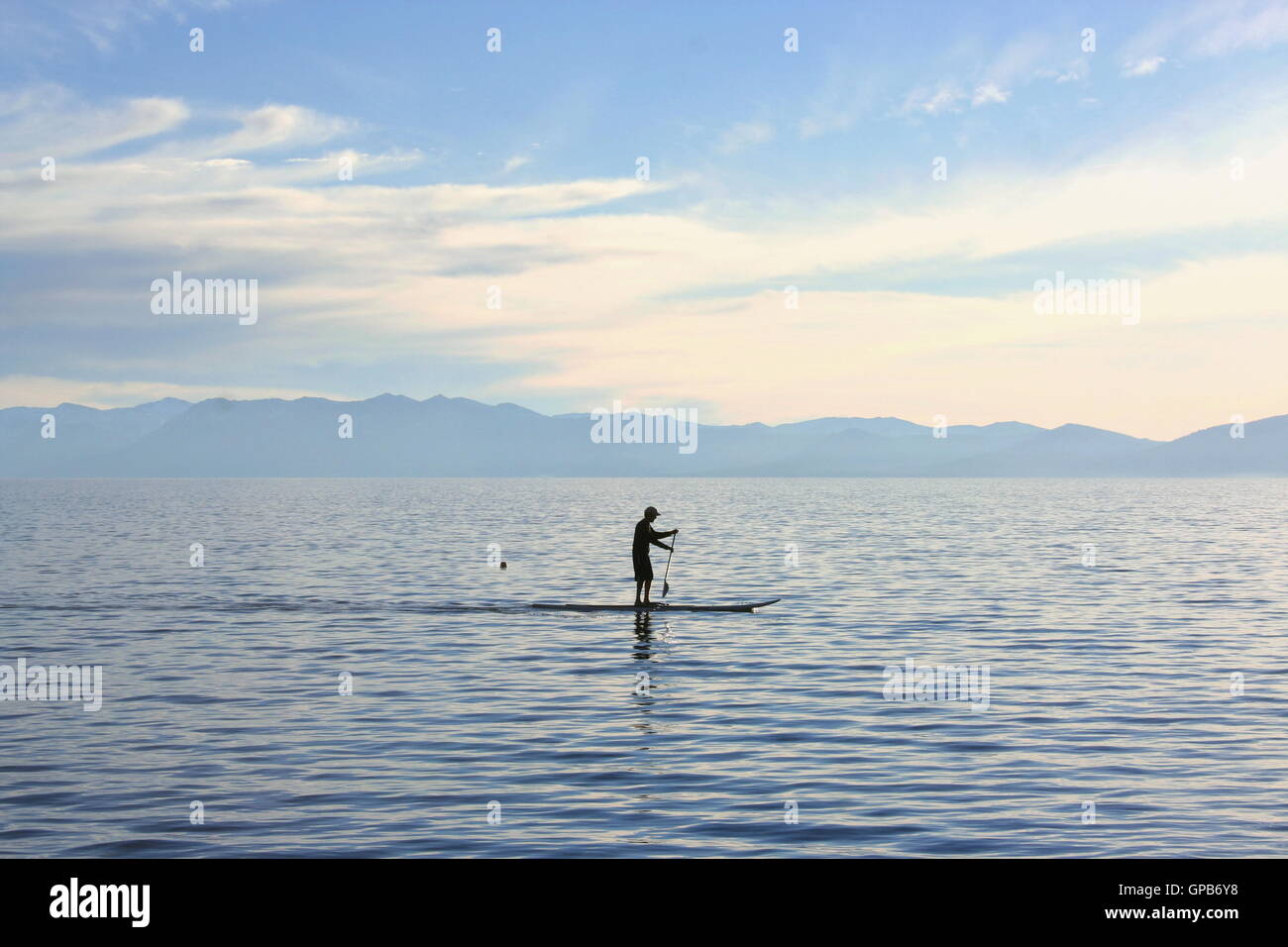 Silhouette d'un homme sur un paddle board, le lever du soleil, le lac Tahoe. Banque D'Images