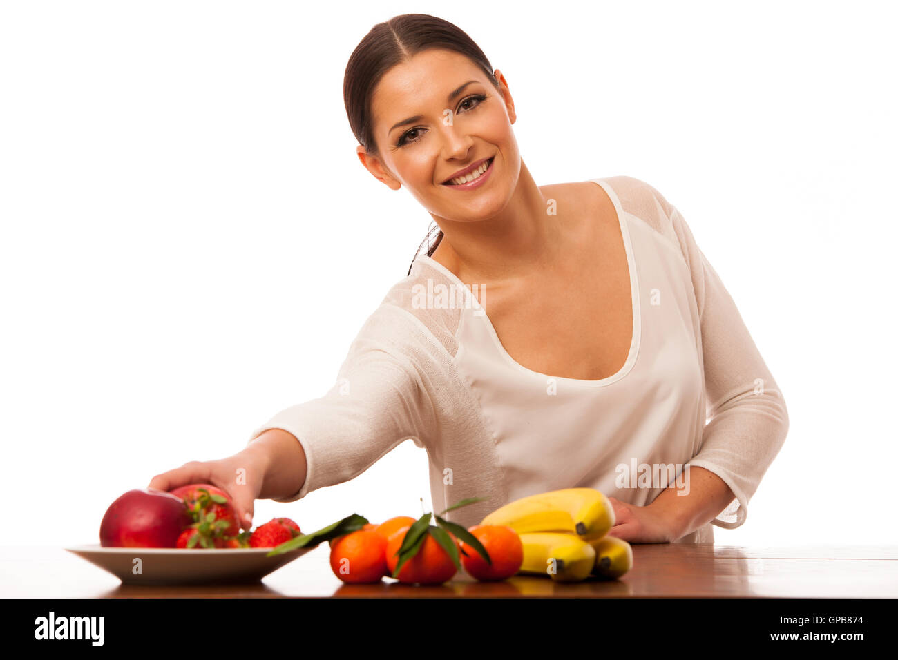 Femme derrière la table pleine de fruits frais la promotion de choix de vie isolated over white. Banque D'Images