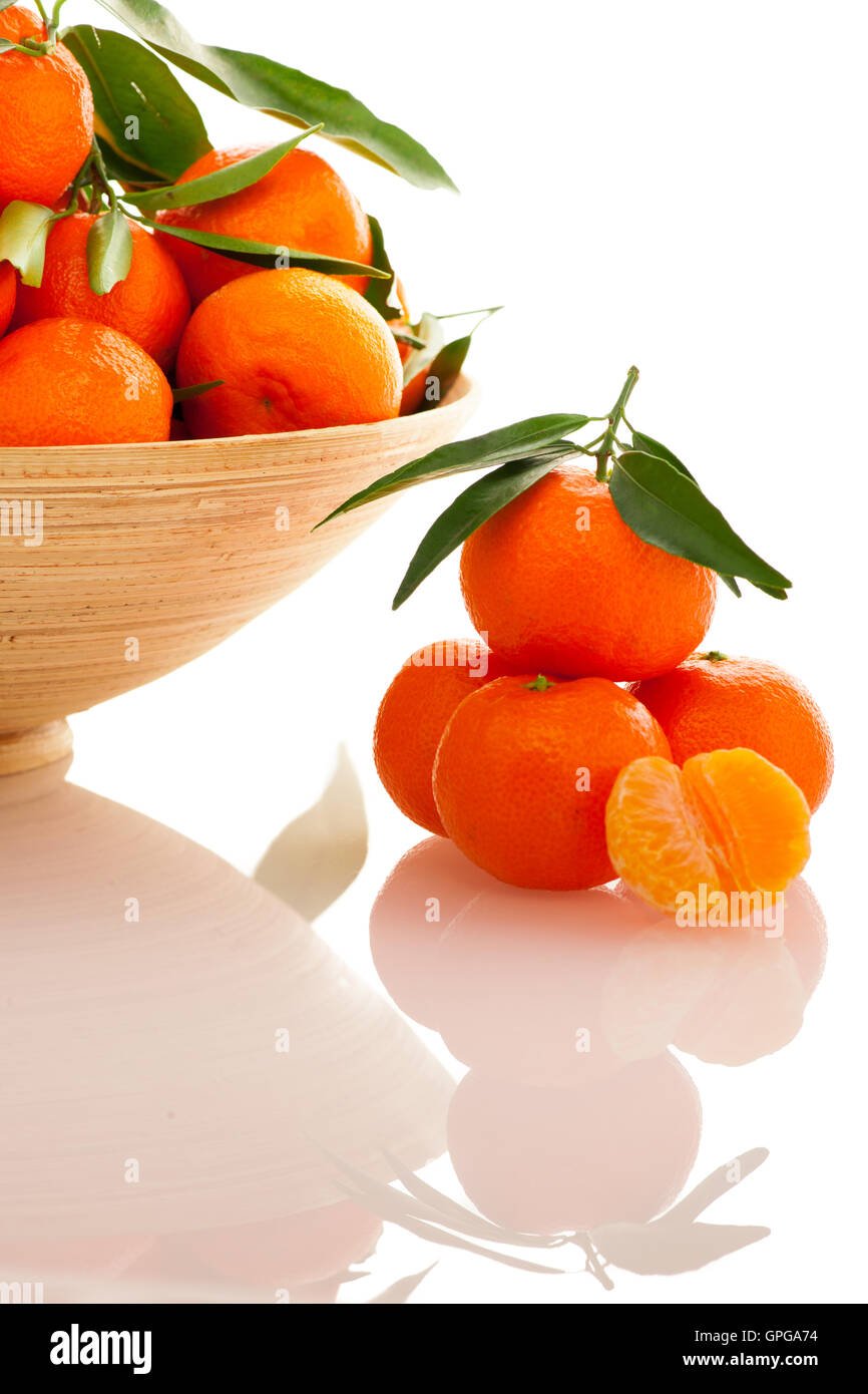 Bol en bois rempli d'agrumes mandarin orange avec des feuilles vertes, isolé sur fond blanc. Banque D'Images