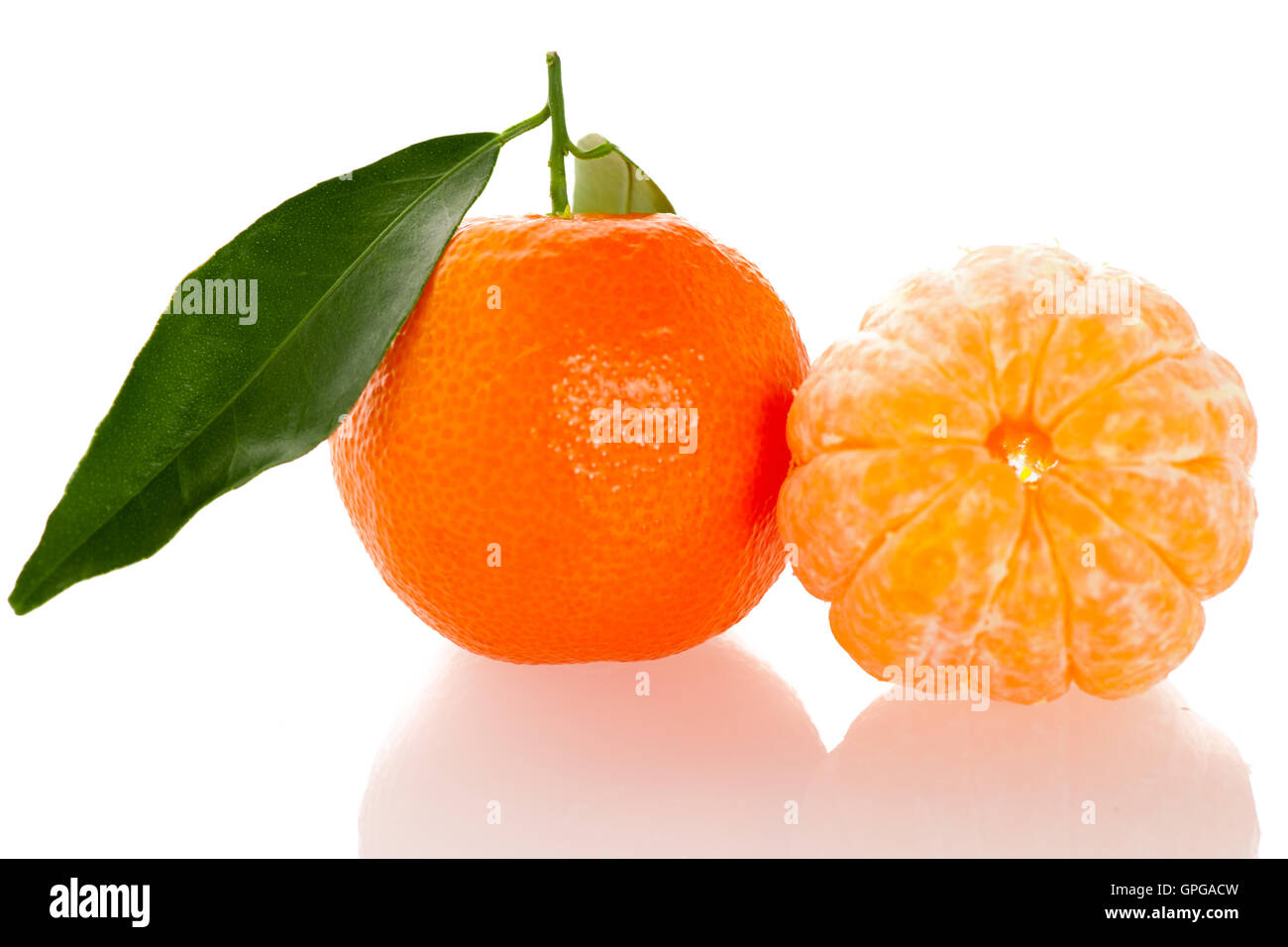 Agrumes mandarin orange fraîches non pelées avec feuilles vertes et la moitié des tranches de fruits pelés isolated over white background. Tasty swe Banque D'Images