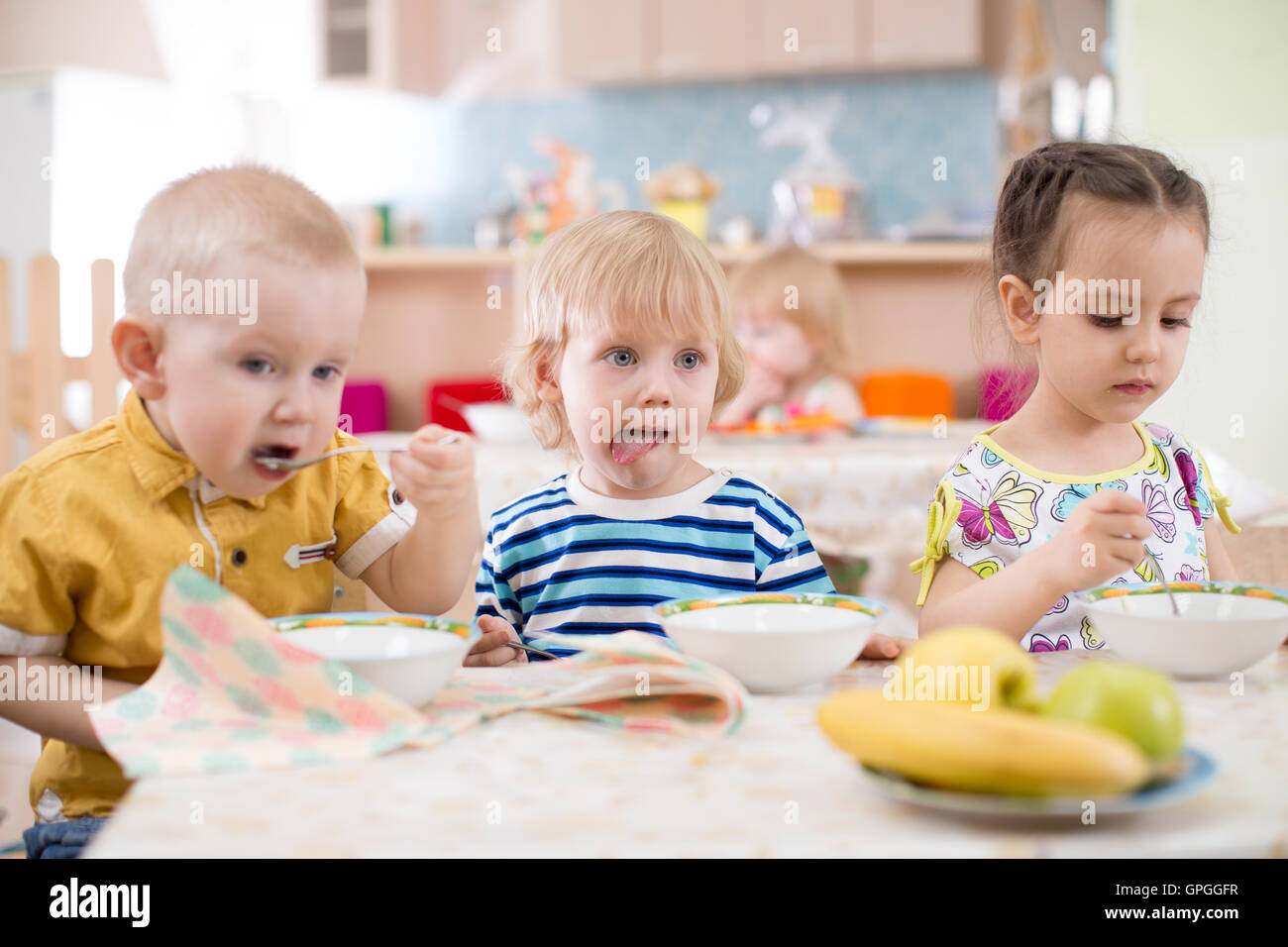 Trois enfants mangeant de plaques dans day care centre Banque D'Images