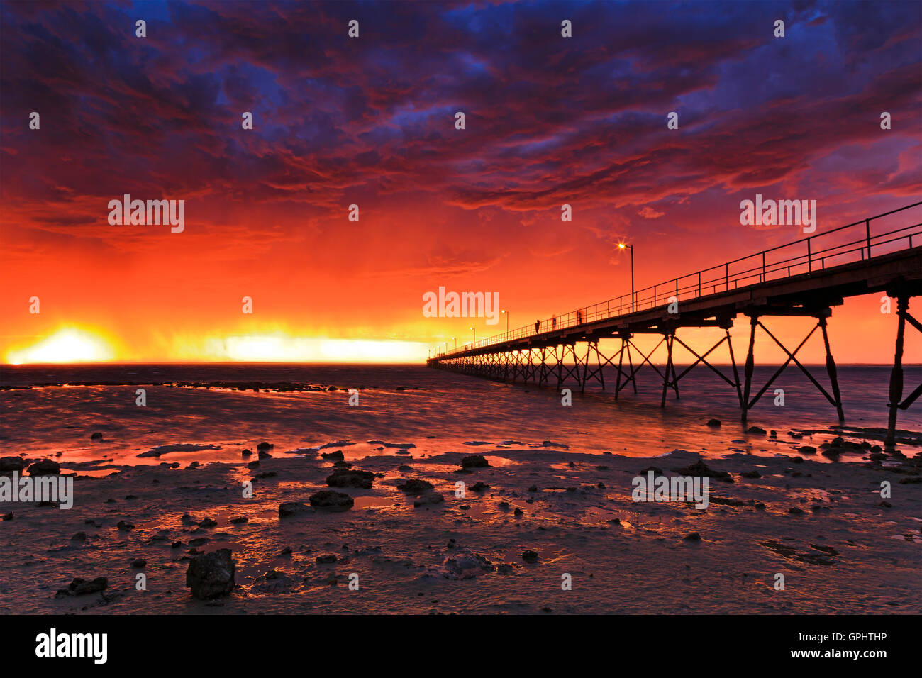 Tempête rouge coucher de soleil sur l'horizon à Ceduna bay sur Grande Baie australienne. Jetée en bois historique en direction d'ouvrir l'eau à marée basse Banque D'Images