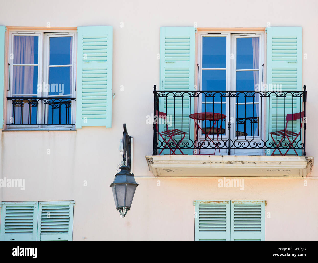 Un balcon avec des chaises et une table et des volets verts aux fenêtres dans le sud de la France Banque D'Images