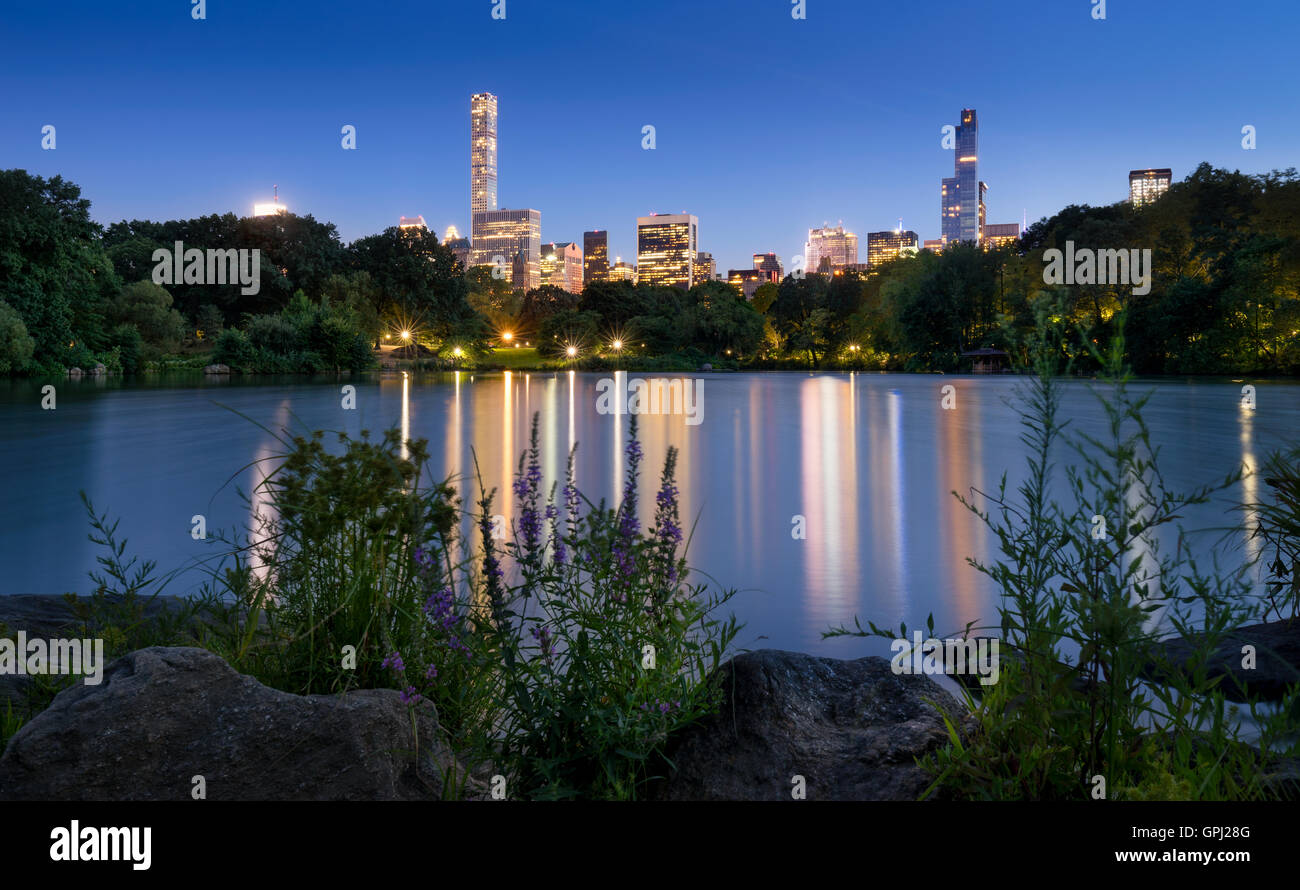 Le lac de Central Park, au crépuscule. Les lumières de la ville de New York et de Manhattan Midtown gratte-ciel reflétant dans le lac Banque D'Images