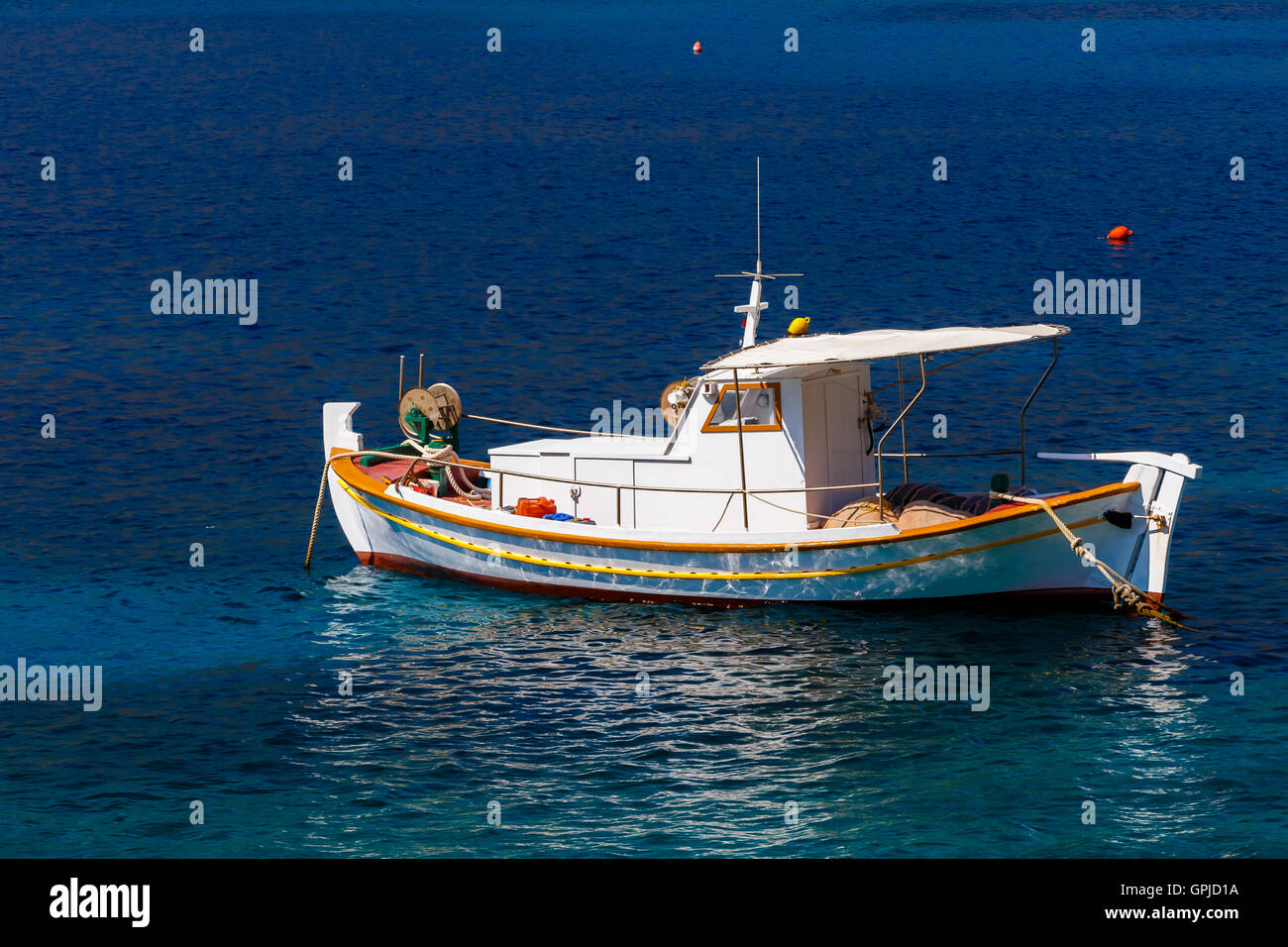 Bateau de pêche traditionnels en bois flottant sur les eaux colorées dans l'après-midi contre les eaux bleues, Laconie, Grèce Banque D'Images