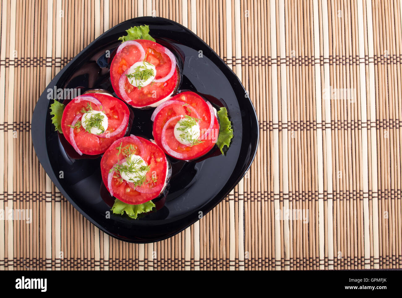 Vue de dessus d'un plat avec des tranches de tomates, la laitue et l'oignon et de nattes de bambou marron Banque D'Images
