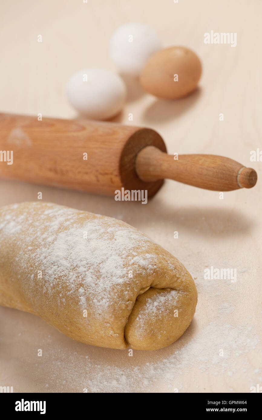 De l'épeautre pâte pour les nouilles sur table en bois et des œufs en arrière-plan. Banque D'Images
