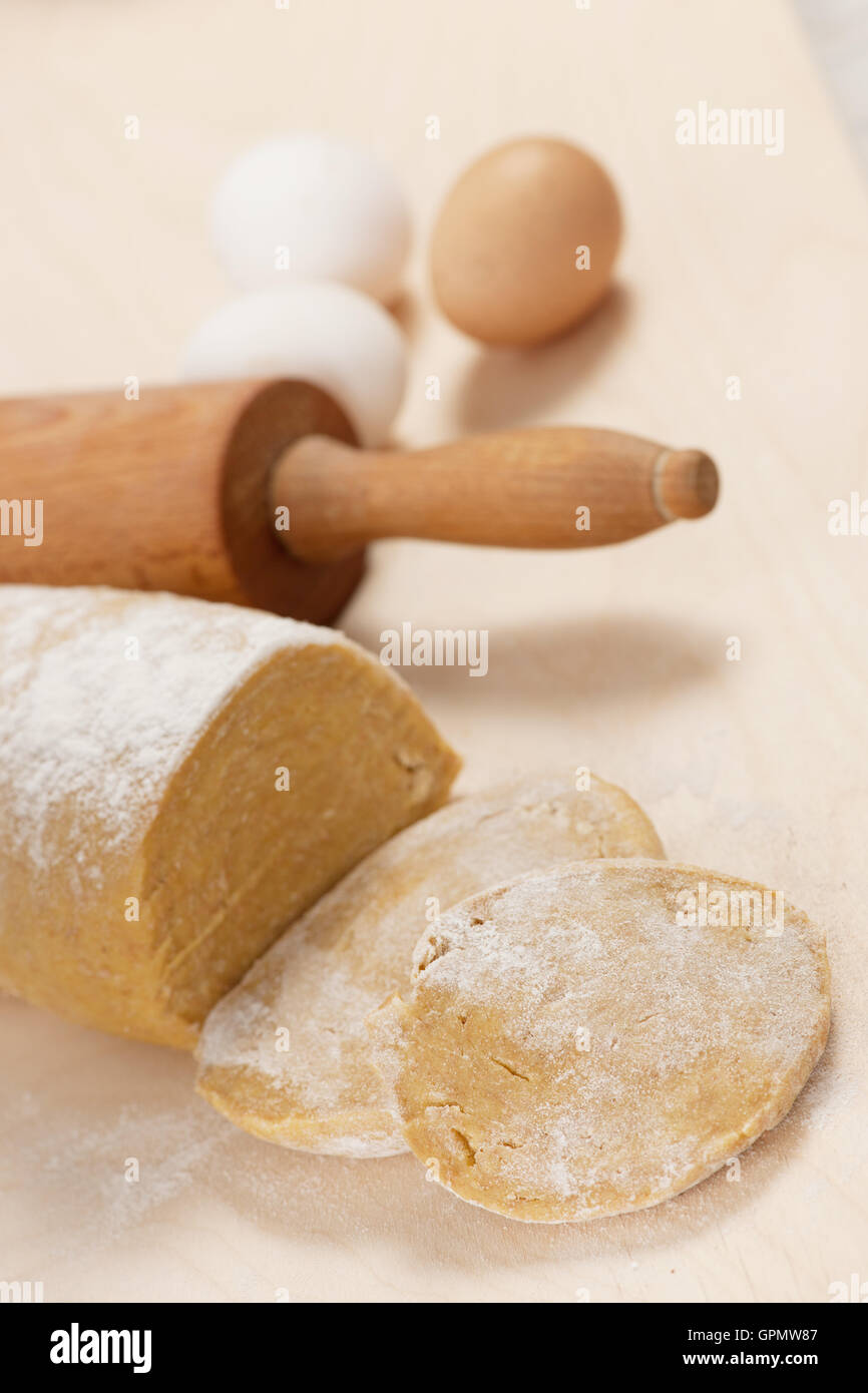 De l'épeautre pâte pour les nouilles sur table en bois et des œufs en arrière-plan. Banque D'Images