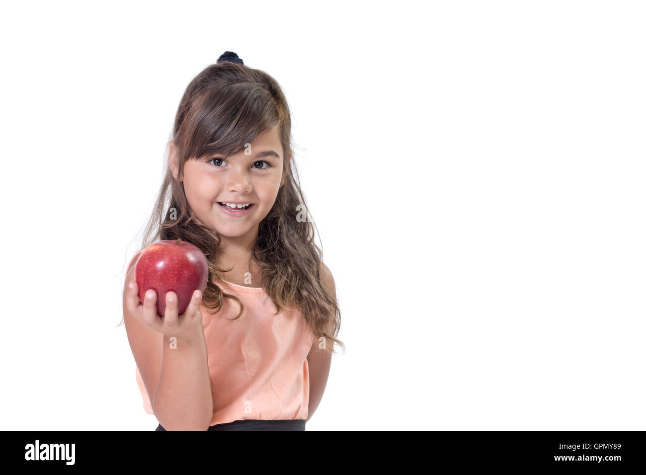 Smiling attractive petite fille offre une pomme rouge. Tout est sur un fond blanc. Banque D'Images