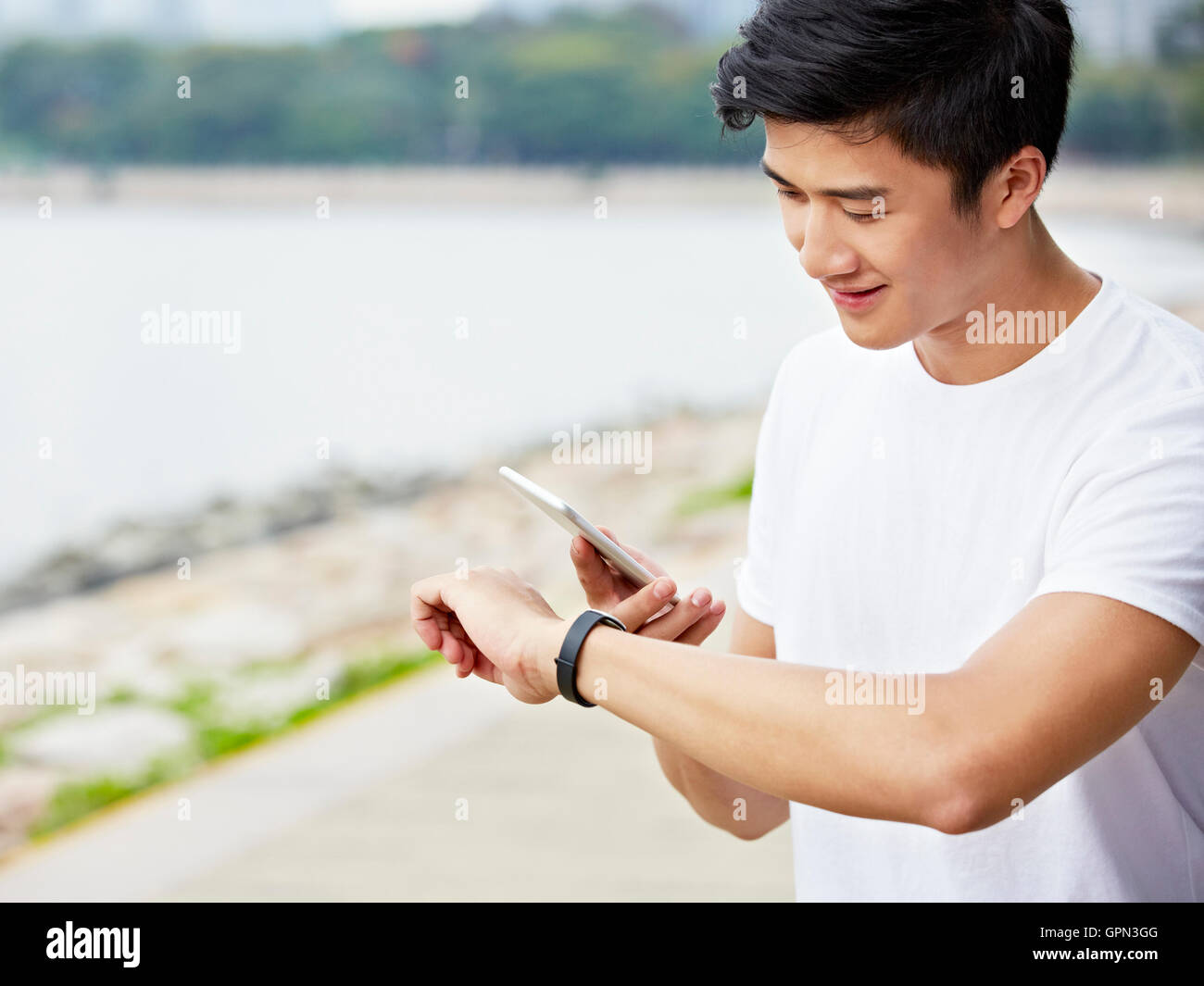 Young Asian man en utilisant les applications de smartphone et smartwatch pour suivre les données d'entraînement pendant l'exercice Banque D'Images