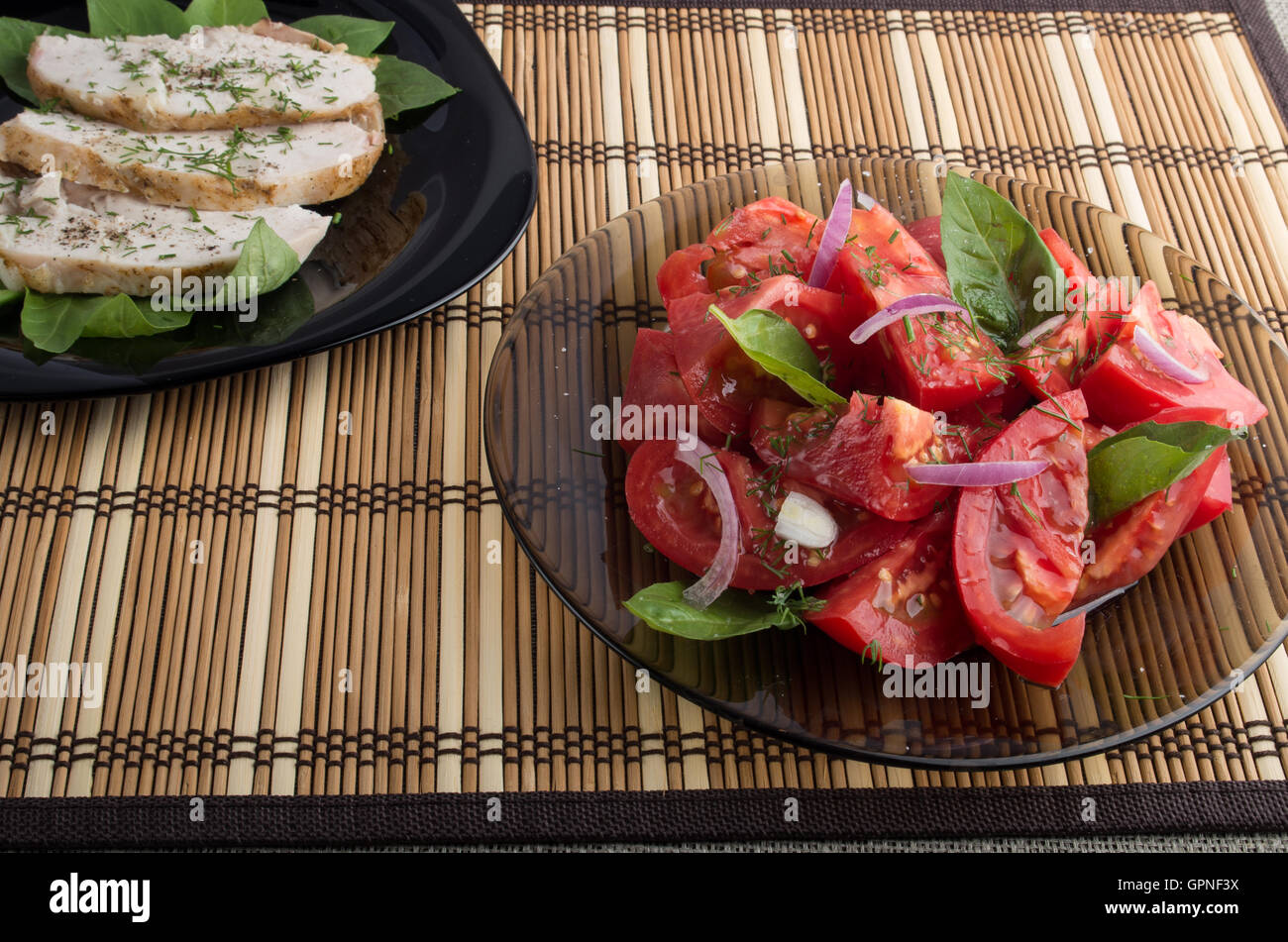 Examen avec un repas fait maison - une salade de tomate verte décoré de feuilles de basilic et de tranches de poulet cuit sur une bande Banque D'Images