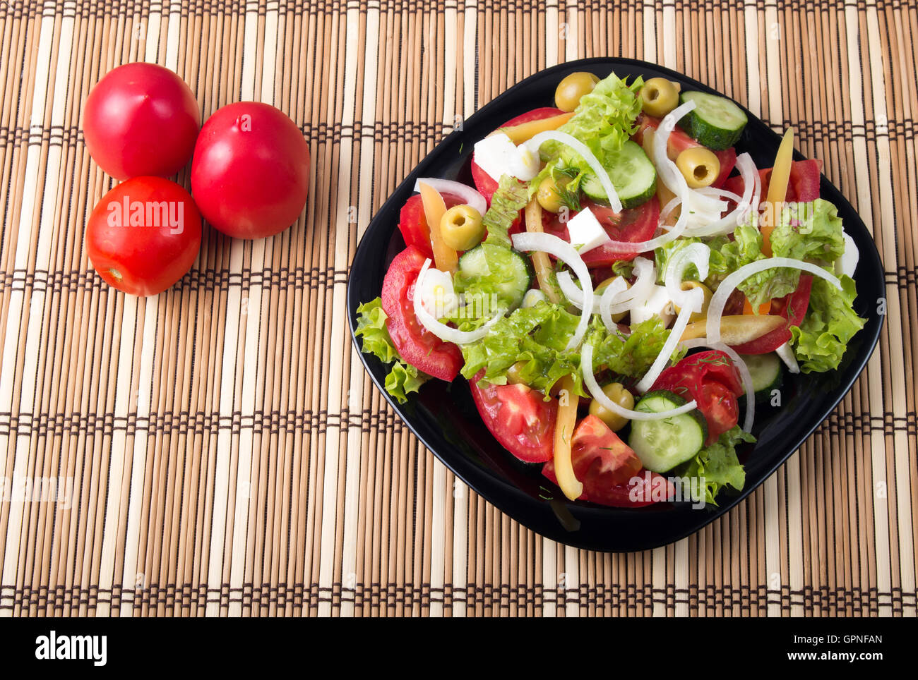 Vue de dessus sur une salade de légumes sains et naturels avec tomates, concombres, olives, oignon, laitue, poivre et huile d'olive sur un fond noir Banque D'Images