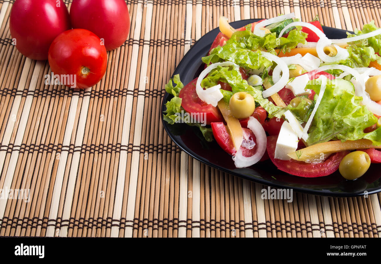 Vue rapprochée de la salade avec des matières naturelles fraîches tomates, concombres, olives, oignon, laitue, poivre et huile d'olive sur une plaque noire et st Banque D'Images