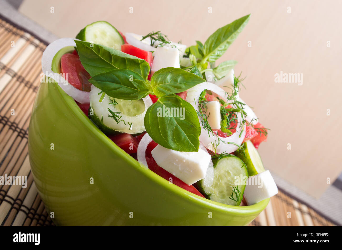 Gros plan sur un livre vert sur le bol avec une salade d'utiles des morceaux de légumes crus hachés Banque D'Images