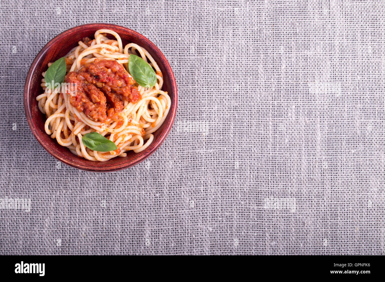 Vue de dessus d'un tapis gris avec une petite portion de spaghetti cuit dans un petit bol en bois de brun Banque D'Images