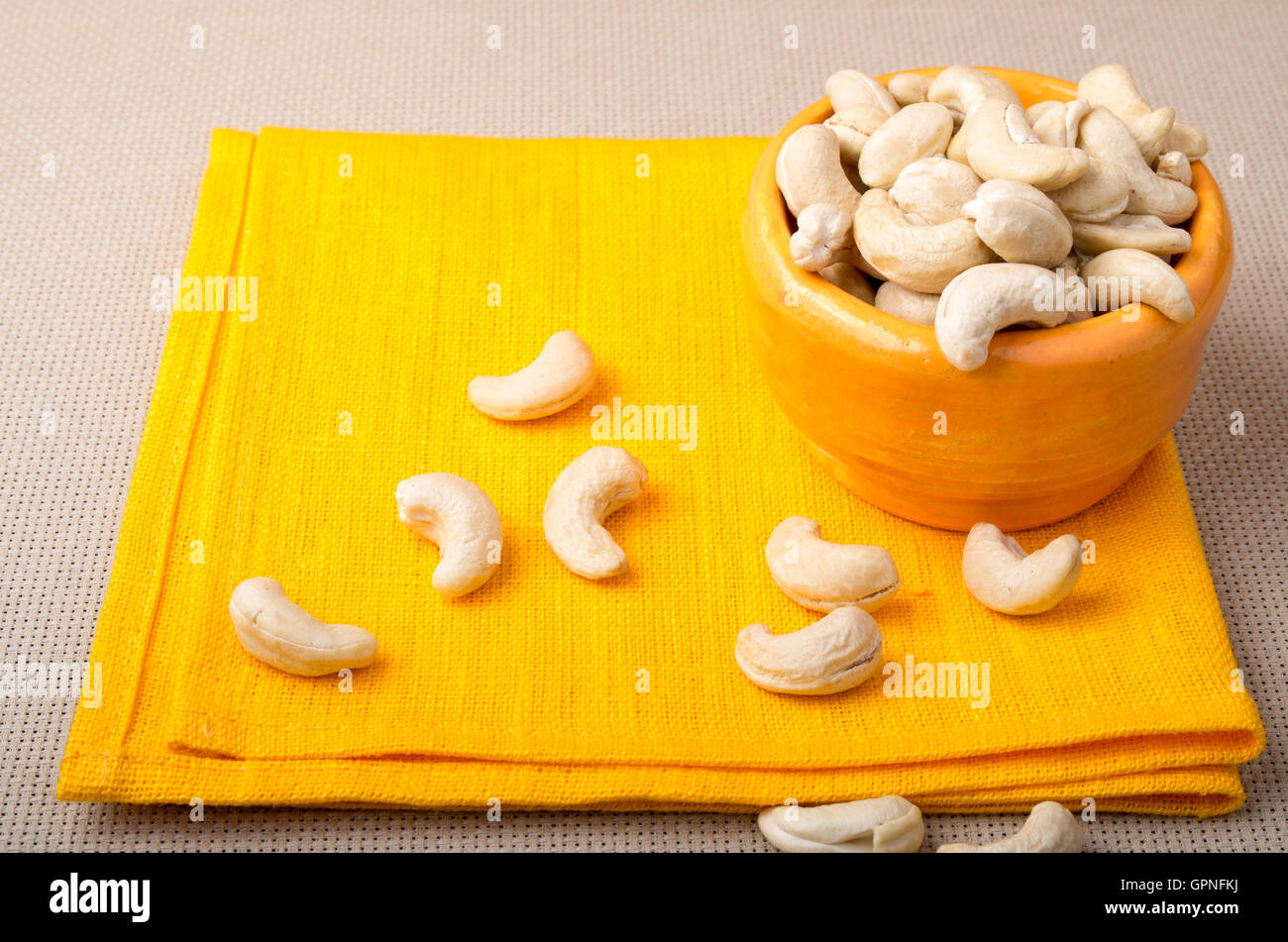 Une alimentation saine et naturelle pour les matières foodists - cajou dans une petite serviette orange orange cup le close-up. Selective focus Banque D'Images