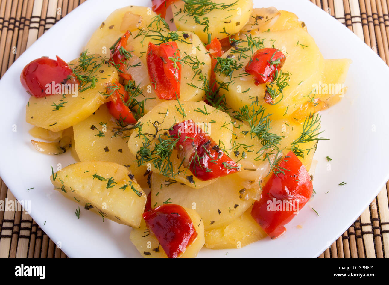 Plan rapproché sur un plat végétarien avec des tranches de pommes de terre cuites et les condiments végétaux sur un fond de bois Banque D'Images