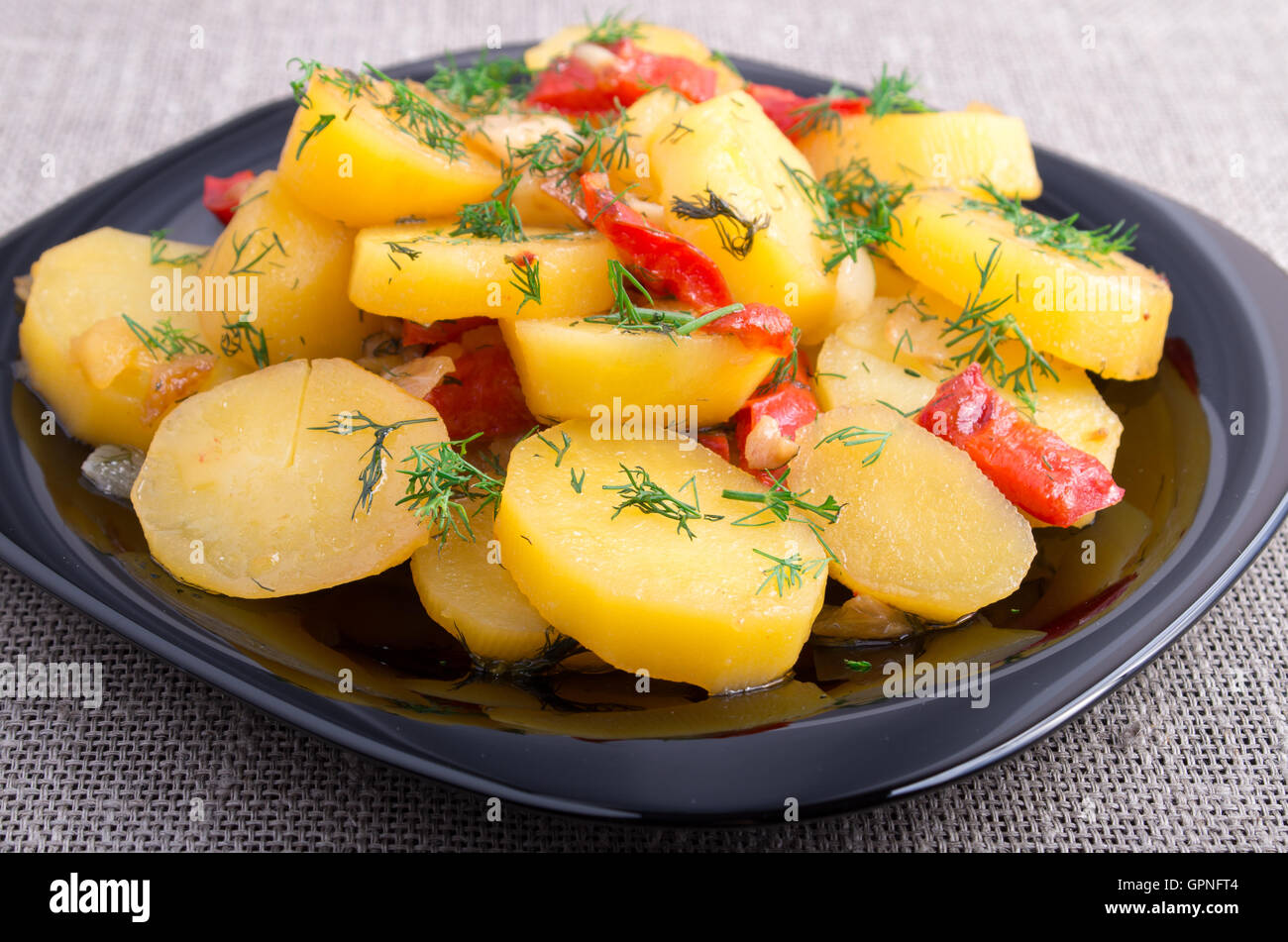 Plan rapproché sur ragoût de pommes de terre avec l'oignon, le poivron et le fenouil sur la surface de la table sur le fond nappe Banque D'Images