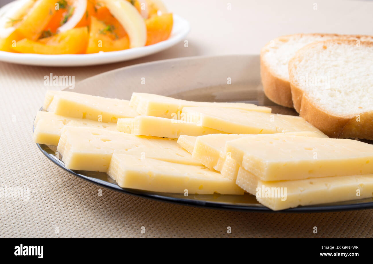 Des collations pour le petit-déjeuner accueil - tranches de fromage et de pain sur une plaque sur une table de salle à manger de près. Focus sélectif. Banque D'Images