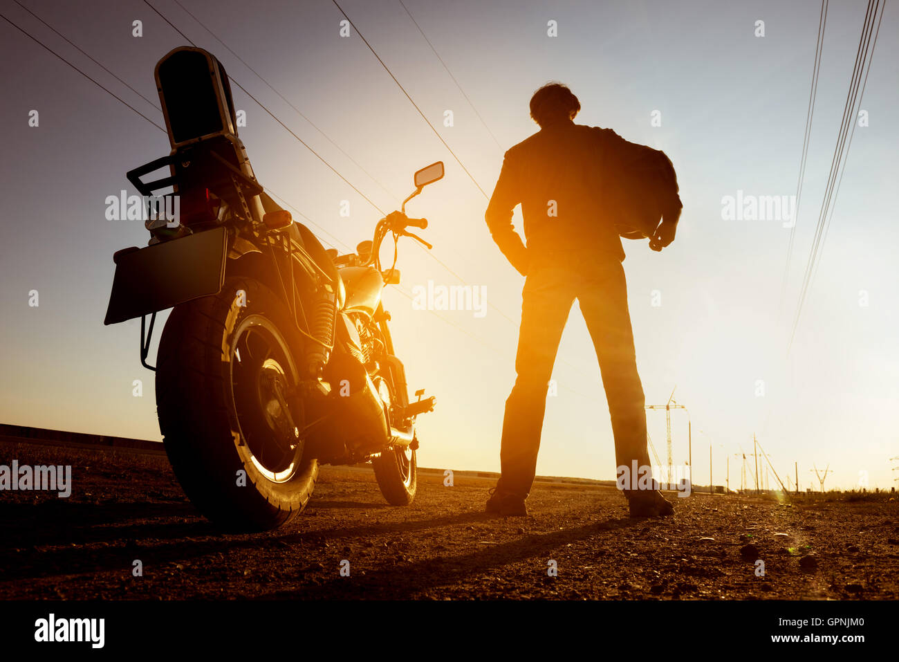 Moto avec motard se dresse sur fond coucher de soleil Banque D'Images