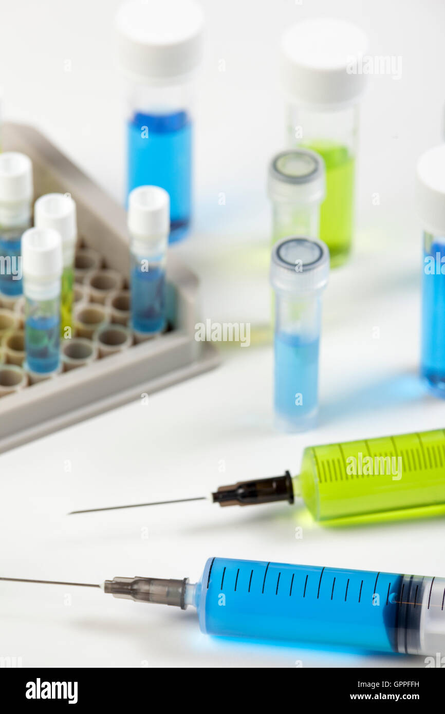 Close up de la seringue contenant un liquide vert et bleu sur fond blanc banc de travail en laboratoire Banque D'Images