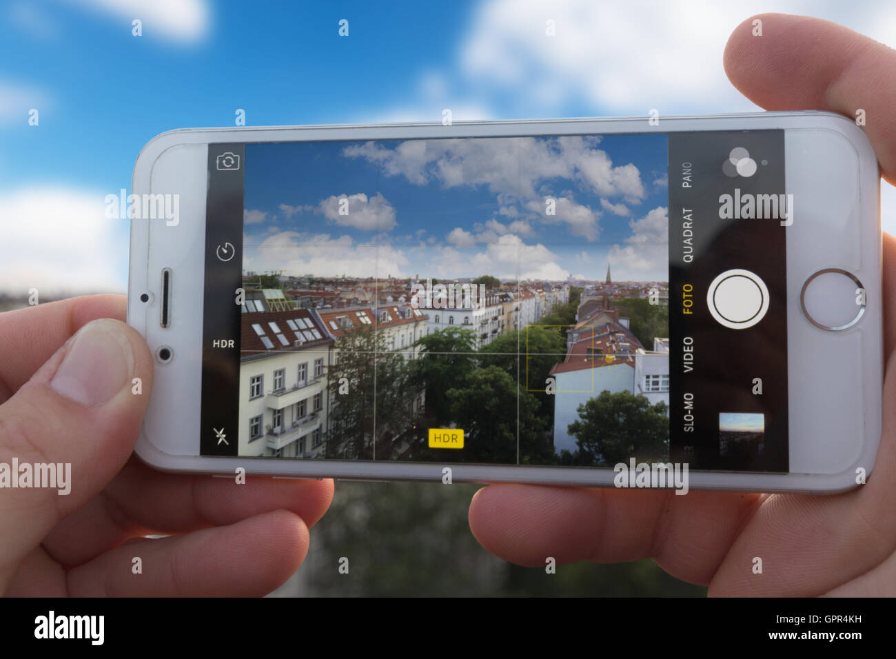 Mains tenant l'Iphone 6, à l'aide d'application Appareil photo pour prendre une photo HDR d'une ville. Banque D'Images