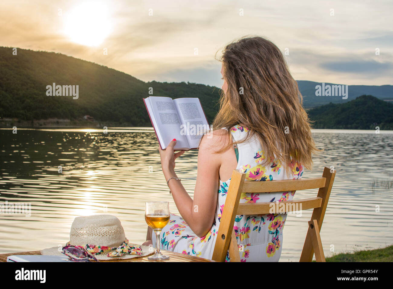 Young Woman Reading a book by the lake Banque D'Images