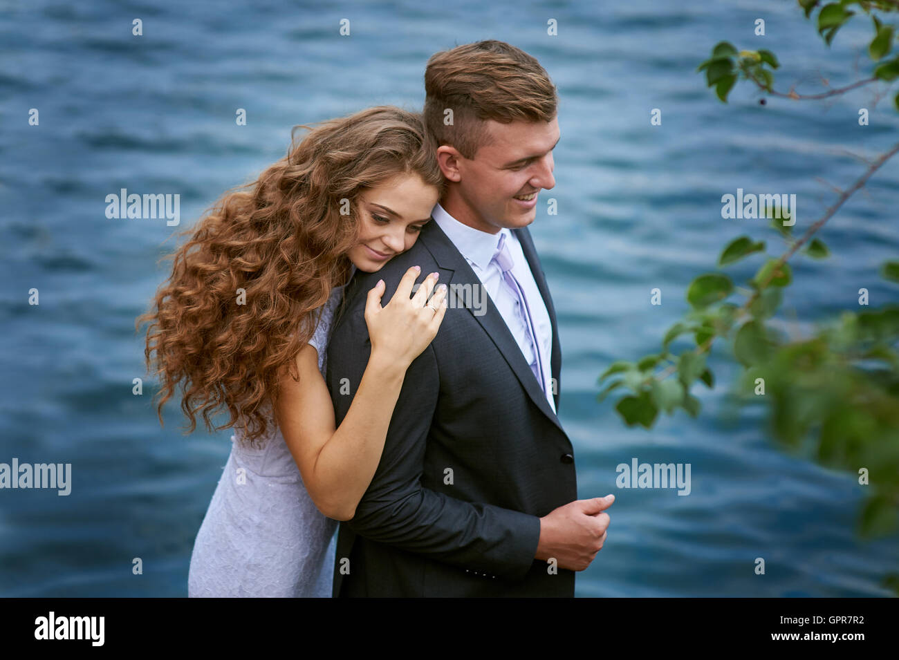 Les jeunes mariés et bride hugging sur le fond du lac Banque D'Images