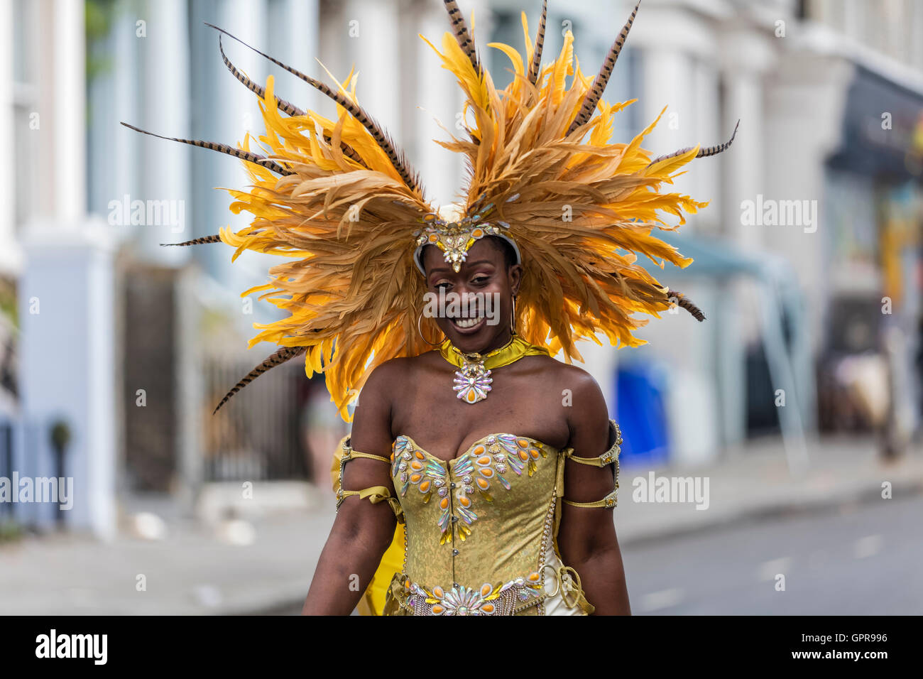 Femme noire portant un costume jaune jaune avec des plumes dans une coiffe à la carnaval de Notting Hill dans l'ouest de Londres Banque D'Images