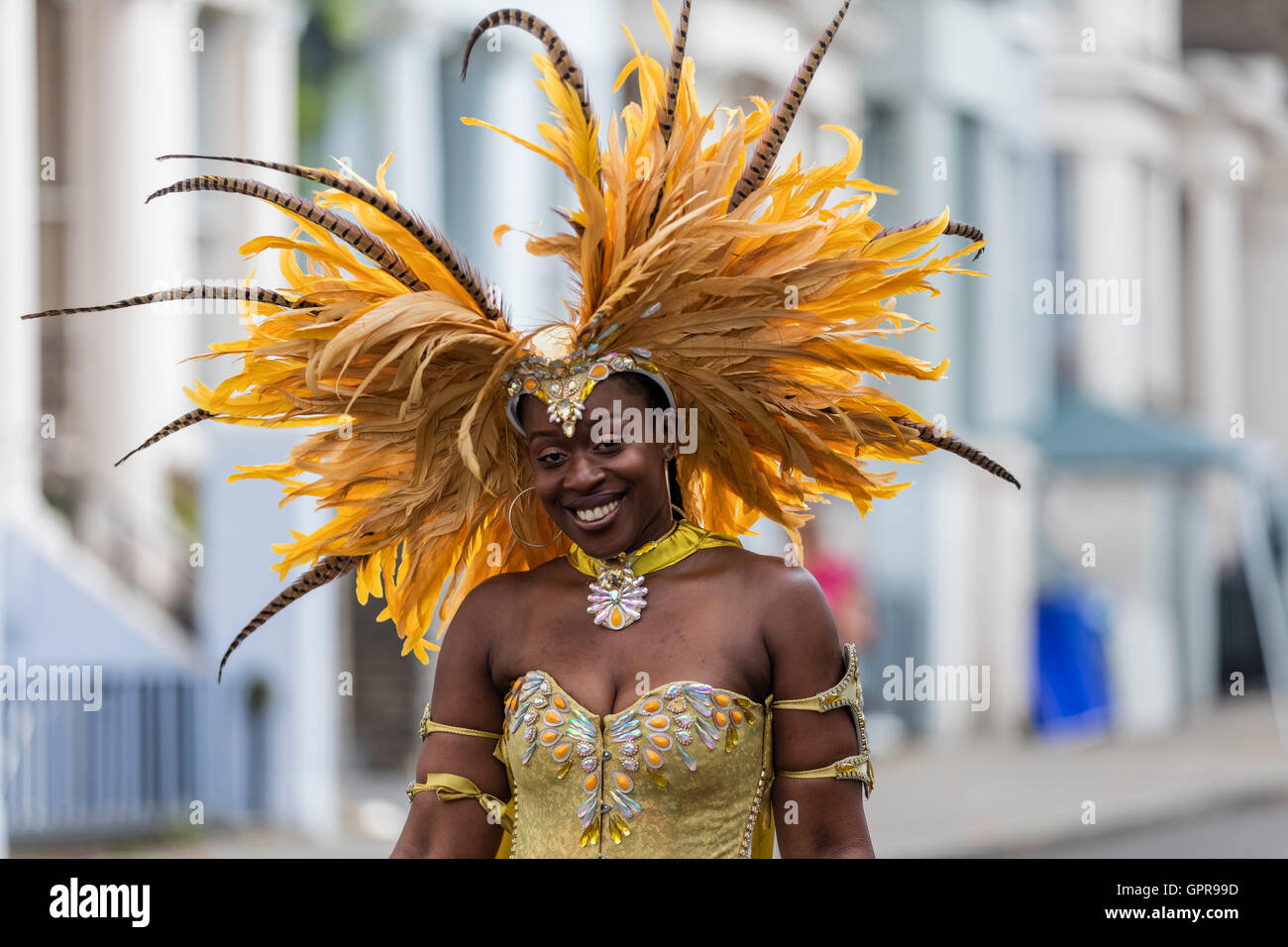 Dame noire en posant pour une photographie de rue et vêtu d'un costume jaune et jaune pour une coiffure de plumes Notting Hill Carnival Banque D'Images
