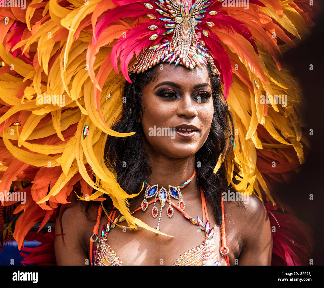 Belle Dame West Indies habillés en costume au Notting Hill Carnival en rouge et jaune feather head dress Banque D'Images
