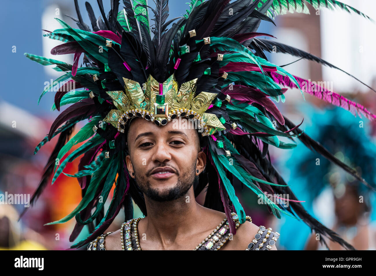 L'homme noir africain avec un noir de couleur turquoise et vert à la coiffure de plumes du carnaval de Notting Hill dans l'ouest de Londres Banque D'Images