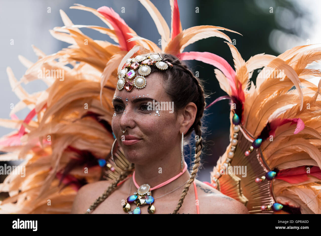 Jeune femme habillé en costume avec peach et coiffe de plumes rouges au carnaval de Notting Hill dans l'ouest de Londres Banque D'Images