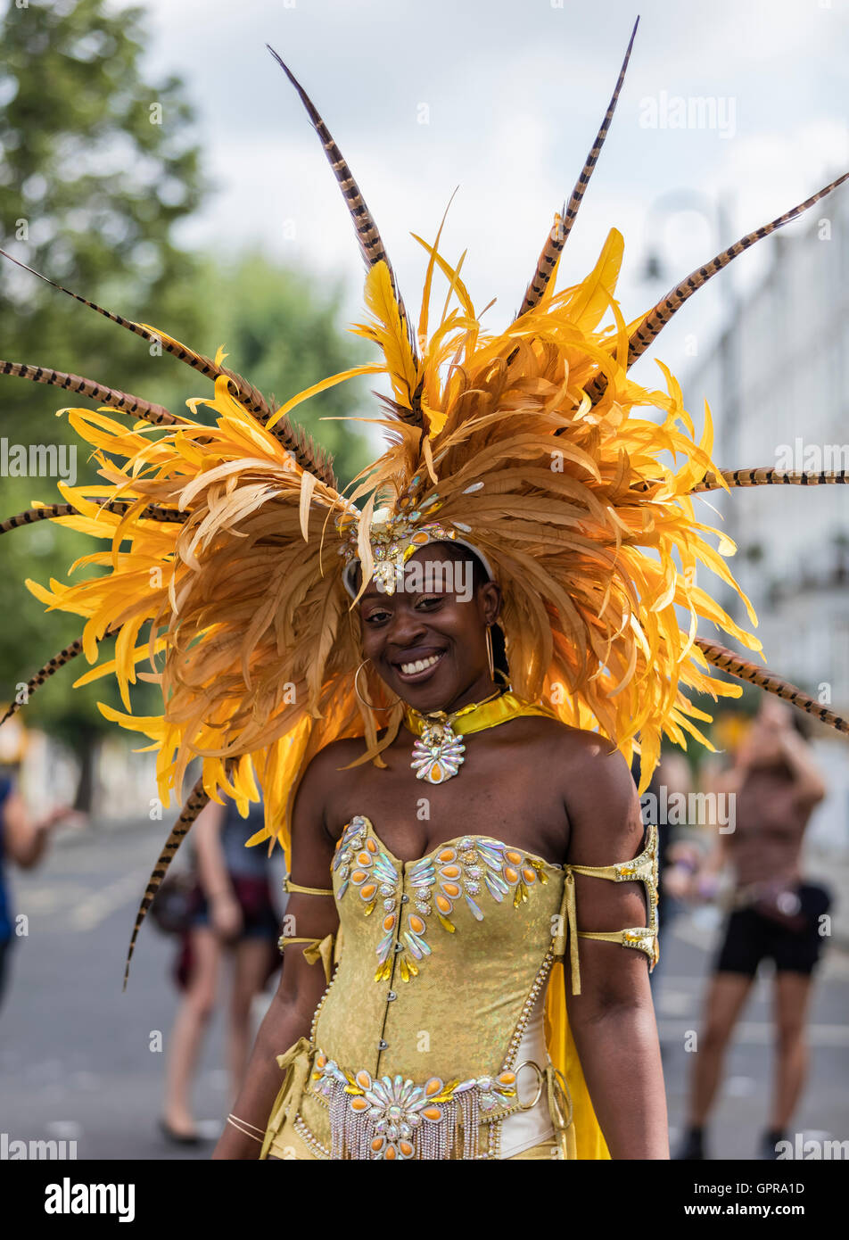 Belle black Antilles Dame vêtue d'un costume jaune Notting Hill Carnival avec coiffe de plumes jaune Banque D'Images