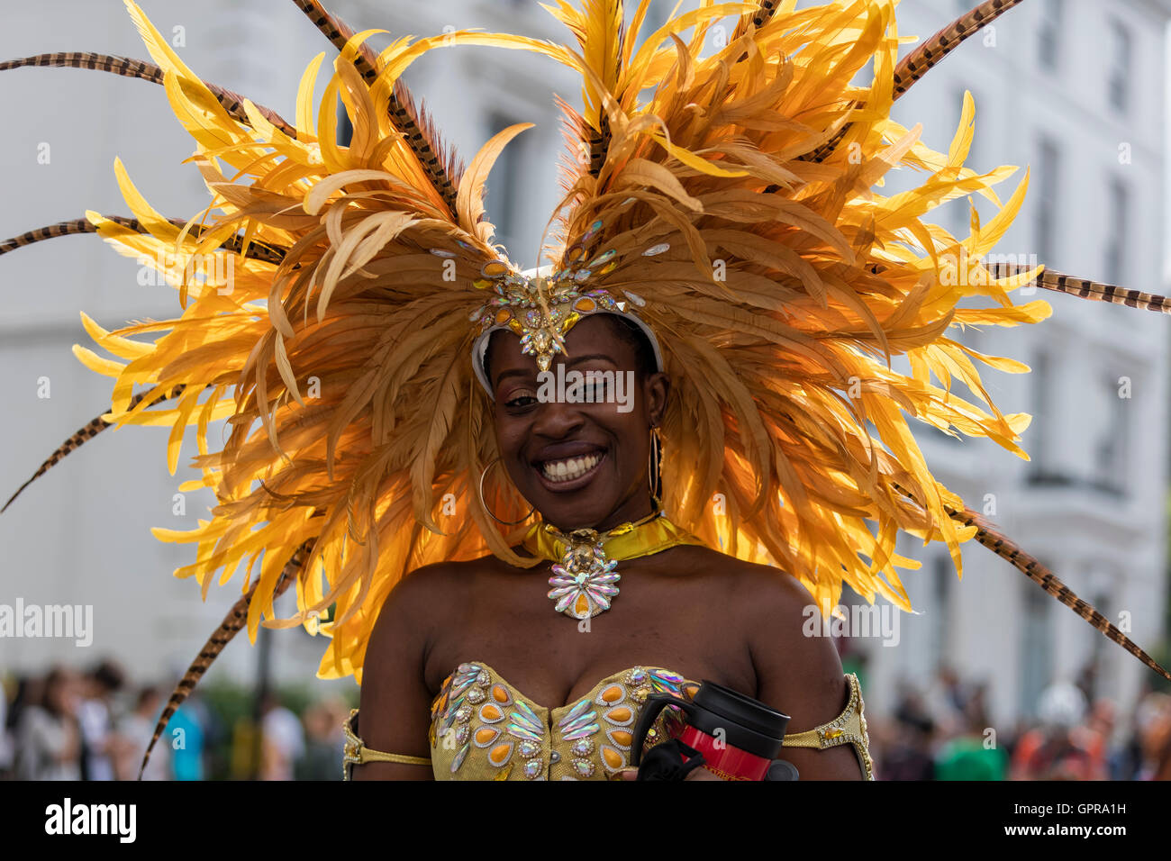 Belle black woman smiling Afro Antillais dans un costume avec des plumes jaunes au carnaval de Notting Hill dans l'ouest de Londres Banque D'Images