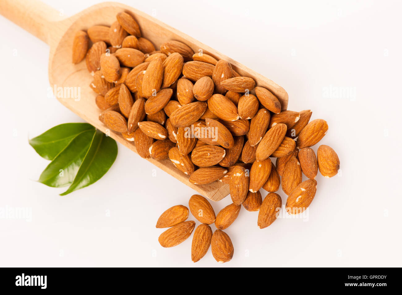 Des tas d'amandes dans une cuillère en bois, casse-croûte santé isolated over white. Banque D'Images