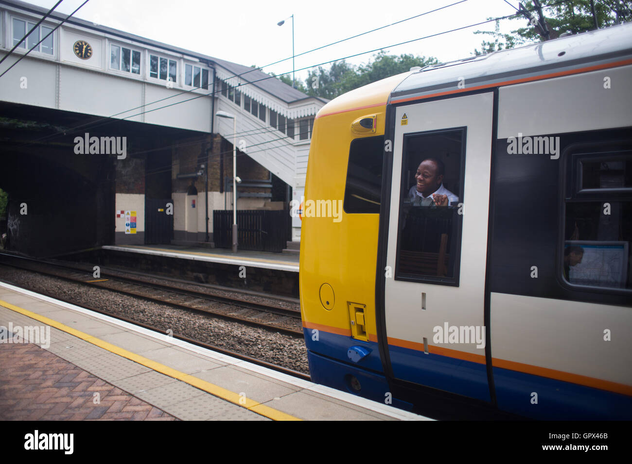 Un conducteur de train s'arrêtant à Brondesbury Park station est d'avoir un rire avec les bases de l'installation du jardin l'Énergie de l'équipage à t Banque D'Images