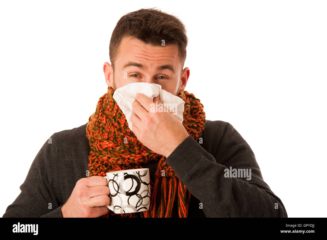 L'homme avec la grippe et la fièvre enveloppé dans l'écharpe holding tasse de thé de guérison avec le mouchoir blanc et isolé au-dessus. Banque D'Images