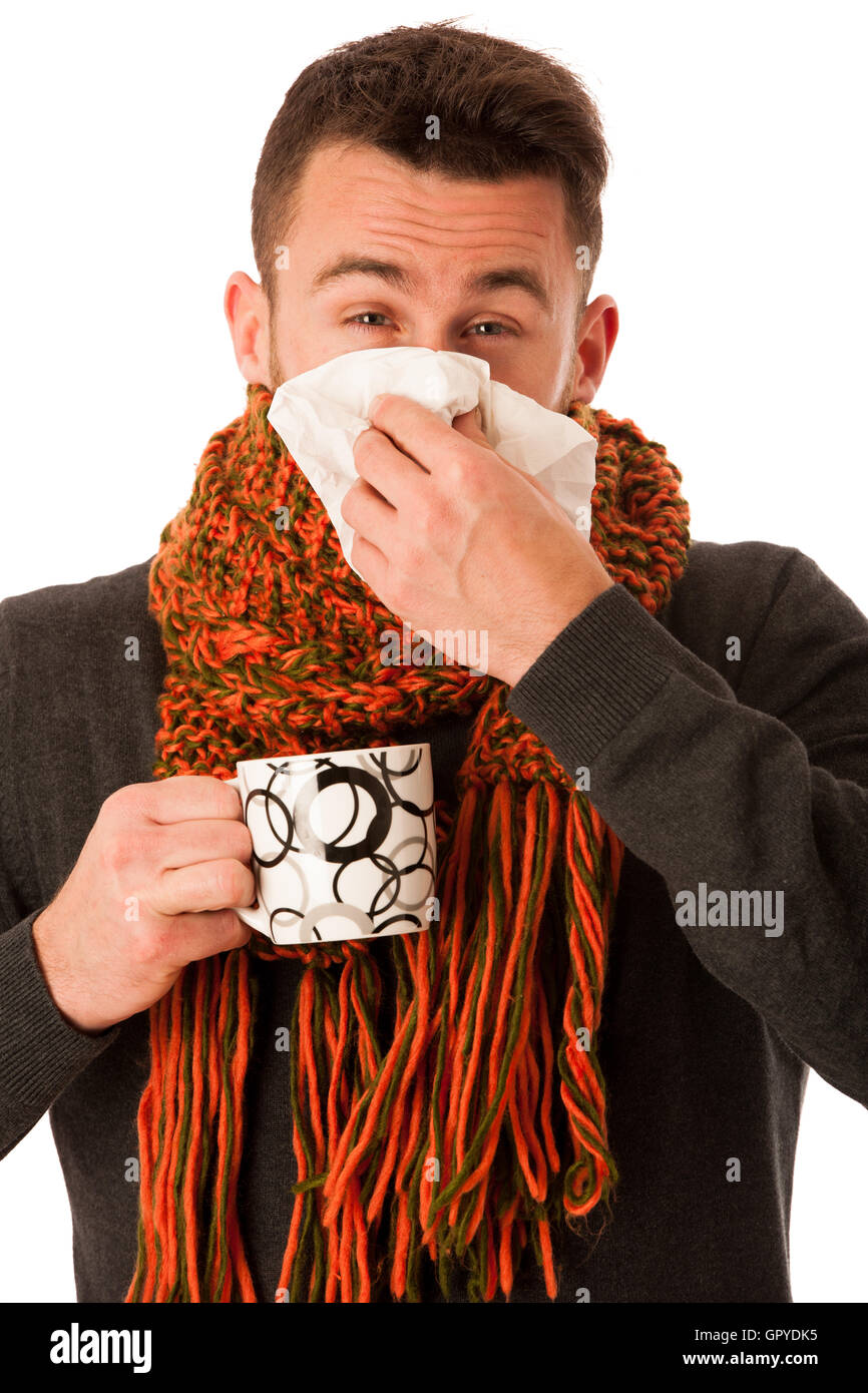 L'homme avec la grippe et la fièvre enveloppé dans l'écharpe holding tasse de thé de guérison avec le mouchoir blanc et isolé au-dessus. Banque D'Images