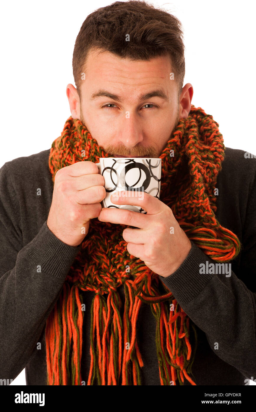 L'homme avec la grippe et la fièvre enveloppé dans l'écharpe holding tasse de thé de guérison avec le mouchoir blanc et isolé au-dessus. Banque D'Images