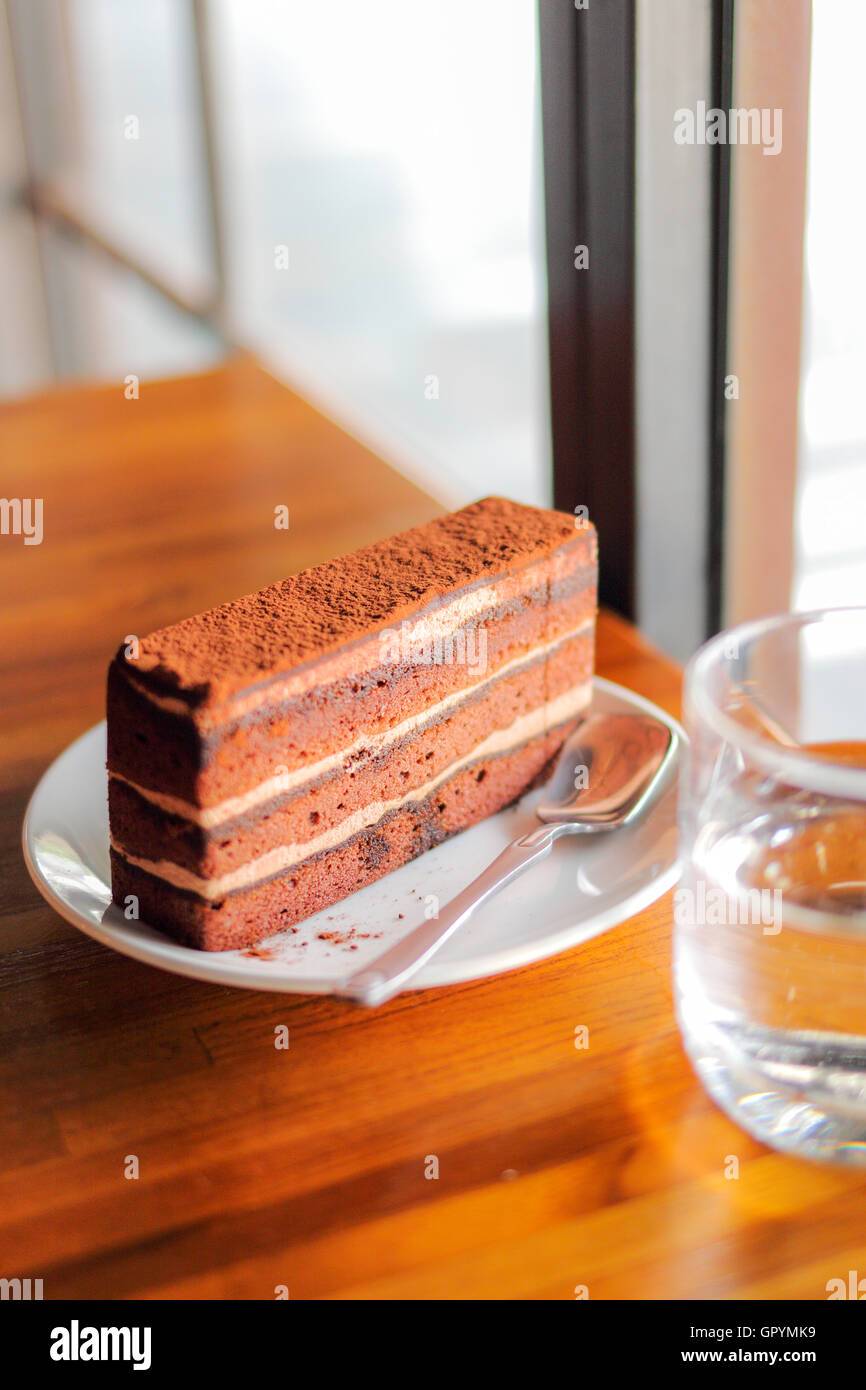 Délicieux gâteau au chocolat en plaque blanche sur table en bois Banque D'Images