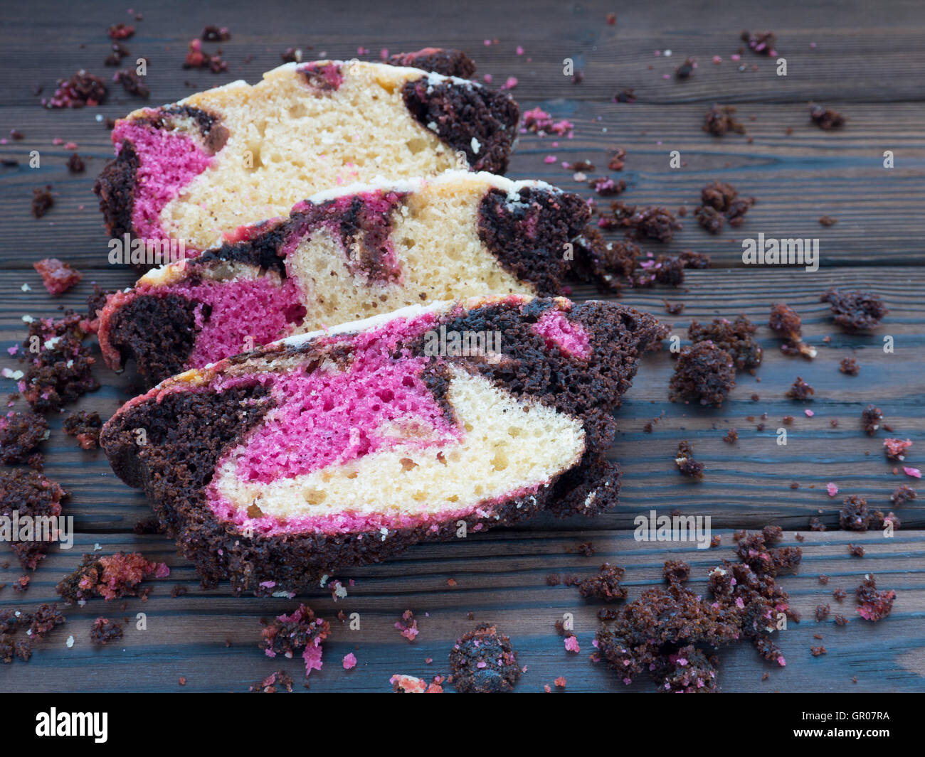 Pink berry et biscuit chocolat tranches et des miettes sur le noir bandes texturées Banque D'Images