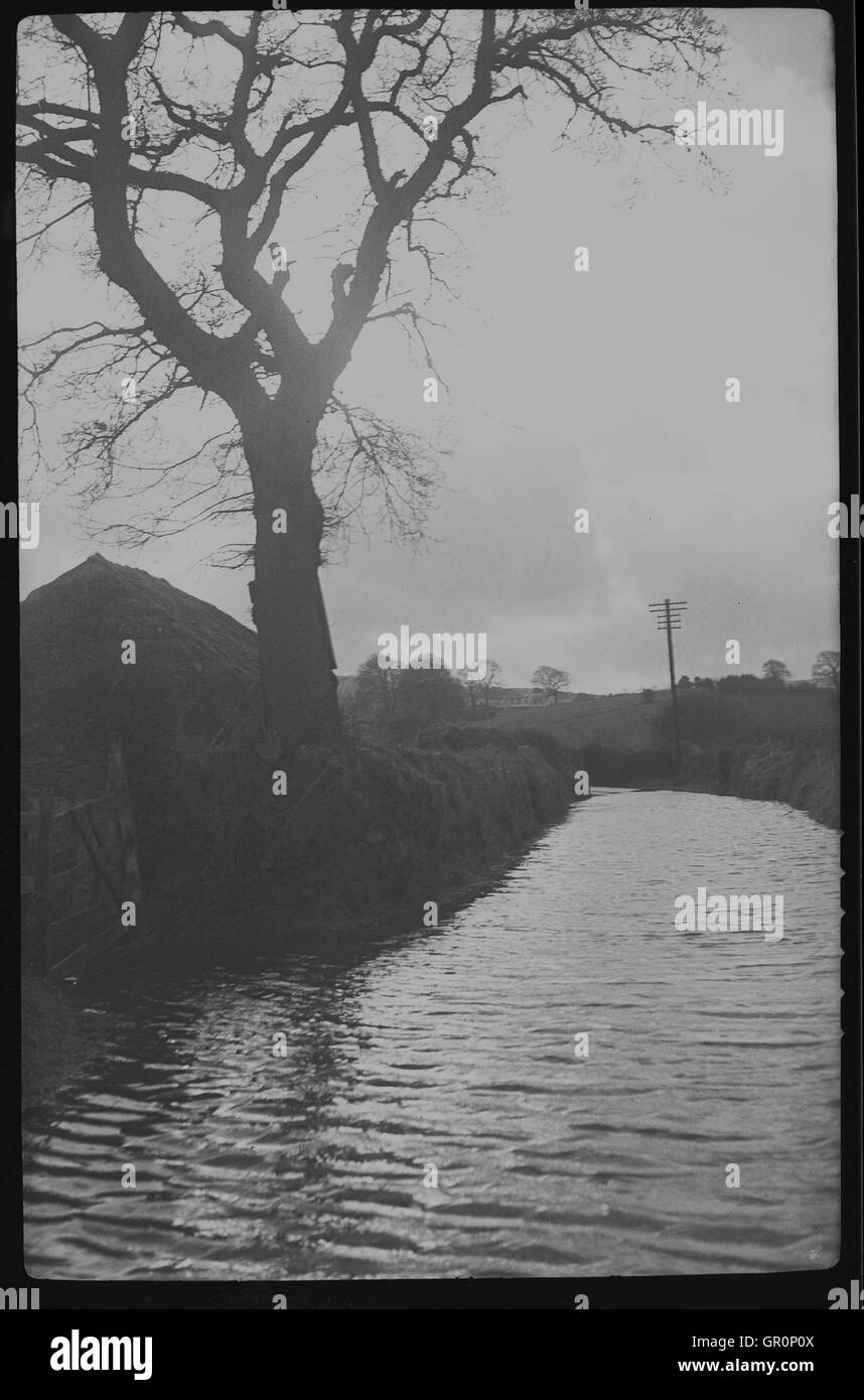 1938, historique, petite livraison de van fait son chemin à travers l'eau sur un chemin de campagne inondée près de Chagford, Devon, Angleterre, sur le bord de la Parc National de Dartmoor et à proximité de la rivière Teign. Banque D'Images