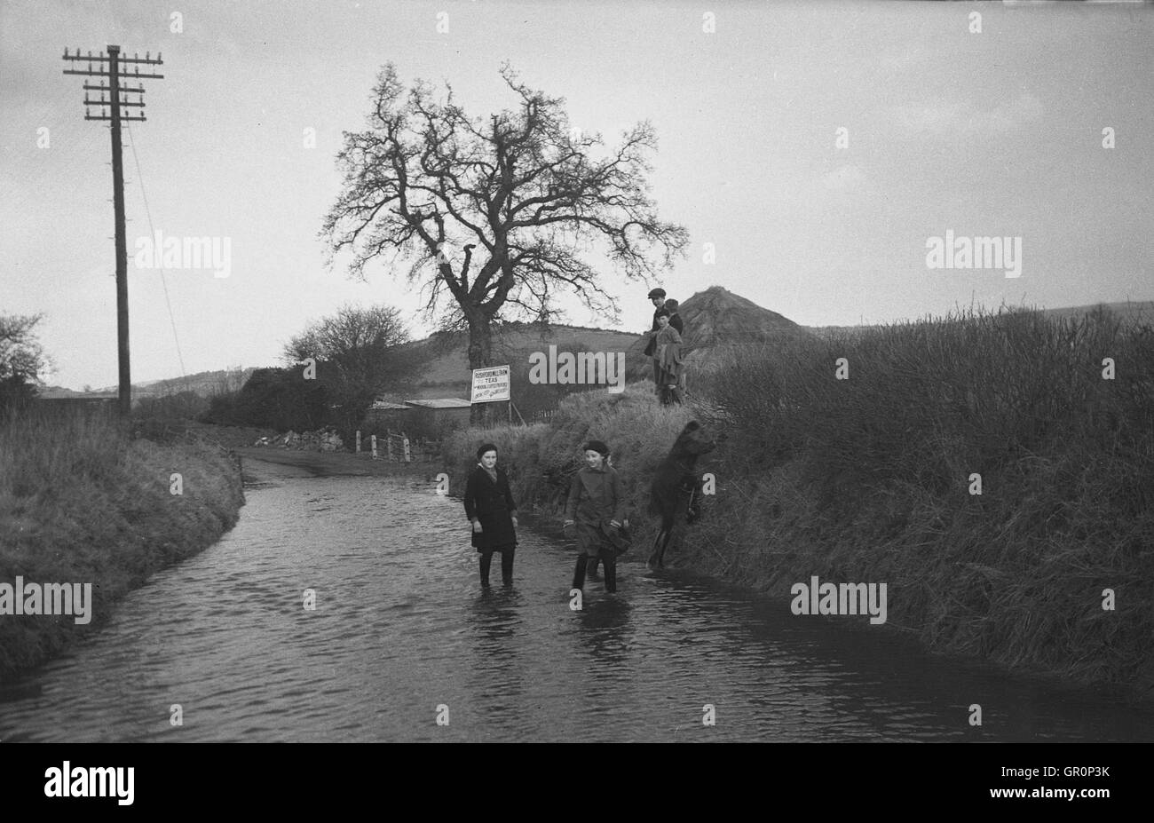 1938, historiques, les villageois patauger dans l'eau sur un chemin de campagne inondée près de Chagford, Devon, Angleterre, sur le bord de la Parc National de Dartmoor et à proximité de la rivière Teign. Banque D'Images