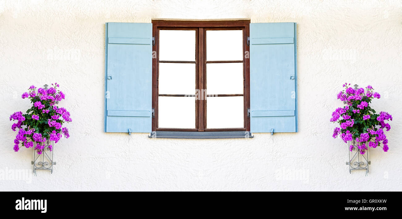 Châssis de fenêtre en bois vides avec des volets bleus et des fleurs sur les côtés Banque D'Images